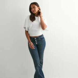 Vit croppad topp med vida ärmar - Säljer en vit croppad topp med bred resår i midjan och vida, korta ärmar. Toppen har en stilren och modern look med rund halsringning och är perfekt för dig som gillar en trendig och avslappnad stil.