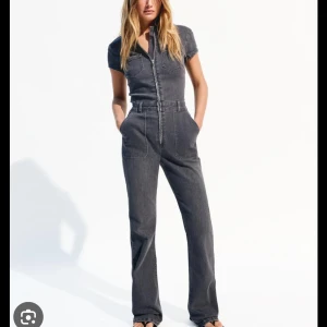 Jeansjumpsuit bershka - Snygg grå jumpsuit i jeansmaterial med raka ben och markerad midja. Dragkedja framtill, korta ärmar och stora fickor både upptill och vid höfterna. Perfekt för dig som gillar en cool och avslappnad stil.