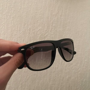 Svarta Ray-Ban Wayfarer solglasögon - Klassiska svarta Ray-Ban Wayfarer solglasögon med bred båge och mörktonade glas. Snygg och tidlös design med Ray-Ban-logga på sidan. Kommer med original brunt fodral. Perfekta för att lyfta din stil under soliga dagar ny pris är 1100 och dessa är för bra pris.