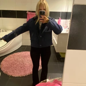 Mörkblå overshirt från 157 - Snygg mörkblå overshirt från 157 med klassisk krage och stora knappar framtill. Jackan har två rejäla fickor på framsidan och är i ett tjockare ullmaterial som ger en cool och stilren look. Perfekt att slänga på över en hoodie eller t-shirt.