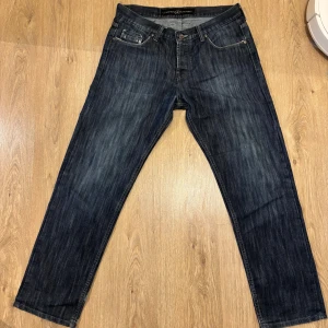 Mörkblå jeansbyxor med raka ben - Snygga mörkblå jeansbyxor från Fashion Factory med raka ben och klassisk femficksdesign. Jeansen har kontrastsömmar och coola detaljer på bakfickorna. Perfekta för dig som gillar en stilren och avslappnad look. Materialet är slitstarkt jeans.