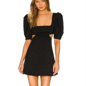 Svart kort klänning med puffärm - Supersnygg svart klänning från Revolve med cut out detalj vid sidorna. Den har en puffärm med pärlor på ärmen. Klänningen är endast använd en gång och har inga tecken på användning! Nypris var ca 2700 kr. Hör av dig vid fler bilder!🩷 (bilden är tagen från Revolve)