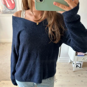 Mörkblå stickad tröja Vero Moda - Mysig mörkblå stickad tröja från Vero Moda med v-ringning och lång ärm. Tröjan har en loose passform och kan bäras offshoulder för en avslappnad känsla.