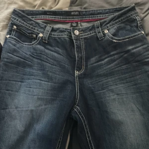 Bootcut jeans med broderade bakfickor - Mörkblå bootcut jeans från ana med snygga broderade och dekorerade bakfickor. Jeansen har kontrastsömmar, klassisk femficksdesign och en glittrig knapp framtill. Materialet är en blandning av bomull, polyester och spandex för extra komfort.                                                            Köpt i usa för 190 dollar 