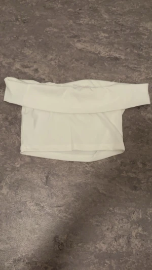 Vit offshoulder croppad topp - Säljer en stilren vit offshoulder topp med croppad passform. Toppen är ärmlös över axlarna och har långa ärmar. Perfekt för dig som vill ha en enkel men snygg look.