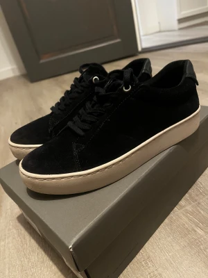 Svarta mockasneakers Vagabond Zoe 37 - Snygga svarta sneakers från Vagabond i modellen Zoe. Skorna har ovandel i mjuk mocka, svarta snören och en vit platt sula som ger en clean look. Perfekta för dig som gillar stilrena och klassiska sneakers med en twist.