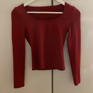 Mörkröd långärmad topp - En stilren mörkröd långärmad topp med rund halsringning. Toppen är stretchig men har även en tight passform och är tillverkad i ett mjukt, stretchigt material som sitter snyggt på kroppen. Man kan ha toppen på vilket håll man vill.