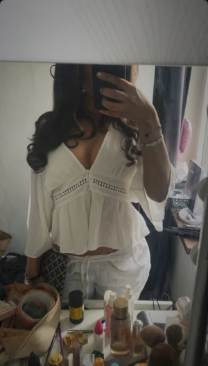 Vit blus från Zara  - Säljer en vit blus från Zara med v-ringad hals och knappar framtill. Blusen har spetsdetaljer under bysten och är tillverkad i ett lätt, luftigt material. Ärmarna är trekvarts och modellen är loose med volang nedtill. Perfekt för dig som gillar romantisk och chill stil.