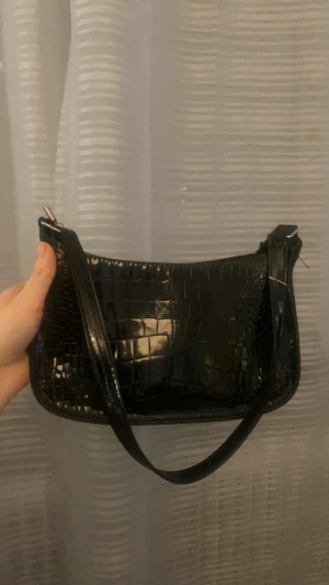 Axelväska glansigt skinn - En glansig axelväska i krokodil mönstrigt skinn, Passar bra till alla stilar och outfits, får plats med allt man behöver varje dag