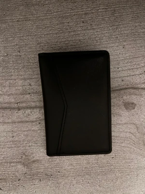 Svart plånbok från Versace i skinn - Stilren svart plånbok från Versace i äkta skinn. Plånboken har flera kortfack och en minimalistisk design med diskret Versace-logga på insidan. Perfekt för dig som vill ha en klassisk och snygg accessoar i fickan.