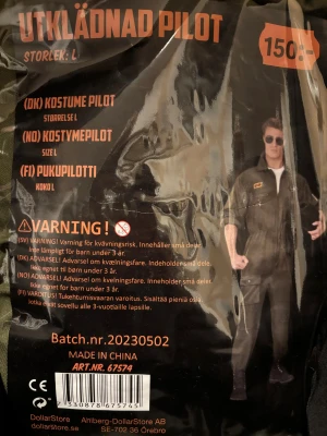 Pilotkostym L med 8th Air Force-märke - Grön pilotkostym i storlek L med dragkedja framtill och broderat 8th Air Force WWII-märke på bröstet. Kostymen har klassisk militärstil och är perfekt för dig som vill sticka ut på maskerad. Materialet är syntet och designen är inspirerad av flygvapenuniformer.