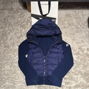 Mörkblå Moncler cardigan - Säljer en skitfet mörkblå cardigan från Moncler! Jackan är väldigt bra skick, och säljs pga att jag har växt ur den! Fler bilder kan lösas. Tar även byten mot en storlek större! Priset ej hugget i sten! 
