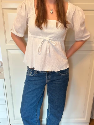 Vit blus med knyt från 157 - Supersöt vit blus från 157 med fyrkantig ringning, puffiga ärmar och knytband i midjan. 🥰