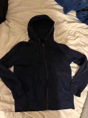 Mörkblå ziphoodie  - Snygg mörkblå hoodie från On Our Terms i storlek M. Den har dragkedja framtill, två stora fickor och justerbar huva med snören. Tillverkad i mjukt bomullsmaterial som är skönt mot huden. 