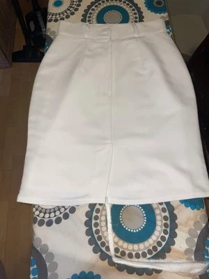 Vit pennkjol i polyester och viskos - Snygg vit pennkjol med slits fram till och hög midja. Kjolen är tillverkad i en mix av polyester och viskos, vilket ger en mjuk och lite stretchig känsla. Stilren och enkel design utan mönster, perfekt för dig som gillar minimalistiskt mode. Lite i storlek så skulle säga att storleken är S