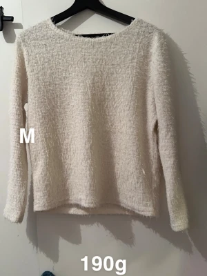 Vit fluffig långärmad tröja M - Säljer en vit fluffig tröja i storlek M med lång ärm och rund hals. Materialet är mjukt och har en lite lurvig textur som ger en mysig känsla. Perfekt för dig som gillar stilrena och bekväma plagg med lite extra struktur.🌸 Fint använt skick. Storlek m