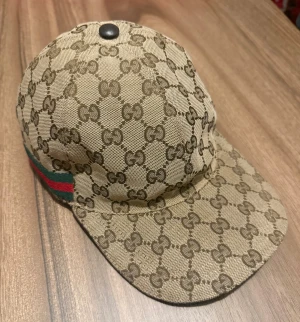 Gucci Keps - Hej! Säljer nu en beige Gucci keps i storlek S, skicket på kepsen är väldigt bra 8/10 skulle jag säga. Kvitto och box har jag inte kvar men garanterar att den är äkta, är öppen till att mötas upp utanför Guccis butik här i Stockholm vid tvivel om att kepsen inte skulle vara äkta. Hör av er vid intresse!