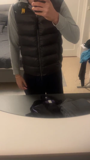 Svart dunväst från Parajumpers - Svart dunväst från Parajumpers med quiltad design och gul detalj vid kragen. Västen har dragkedja framtill och insida i ljusgrått. Perfekt för lager-på-lager och har en clean, sportig look. Pris kan diskuteras.