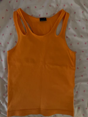 Orange linnetopp från Gina Tricot - orange linnetopp från Gina Tricot i storlek S. Toppen har klassisk racerback och ärmlös design. Materialet är mjuk bomull. Enkel och stilren utan mönster eller detaljer.