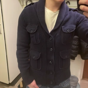 Blå stickad cardigan - Otroligt fet unik blå stickad cardigan. Perfekt nu till kallare väder. Modellen är 180cm, 74kg. Priset kan såklart diskuteras!