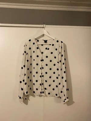 Prickig blus från Lindex - Vit prickis blus från Lindex. Långärmad och tillverkad i ett lätt, men lite genomskinligt material. 