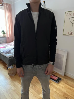 Unik* svart cardigan - Eftertraktad svart cardigan jacka ifrån indicode jeans. med hög krage och hel dragkedja framtill. Jackan har ett stilrent axel märke på vänster ärm och två sidofickor. Materialet är mjukt och lätt, perfekt för lager-på-lager. Passformen är normal och designen är enkel utan mönster.