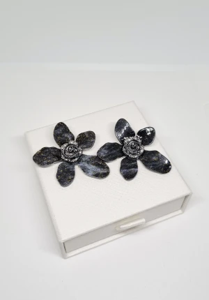 Svarta blommiga örhängen med glitter - Unika örhängen i form av stora blommor med fem kronblad, svarta med skimrande guldglitter och silverfärgad ros i mitten. Tillverkade i plast och metall, fästs med stift. Perfekt för dig som gillar statement-smycken och coola detaljer.