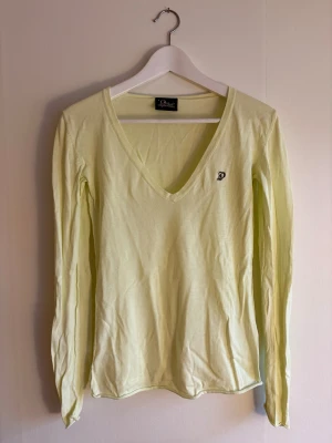 Ljusgul Peak Performance v-ringad tröja - Ljusgul långärmad tröja från Peak Performance med v-ringad hals och broderad P-logga på bröstet. Tillverkad i mjuk bomull, perfekt för dig som gillar enkel och clean stil. Äldre modell från Peak performance. 