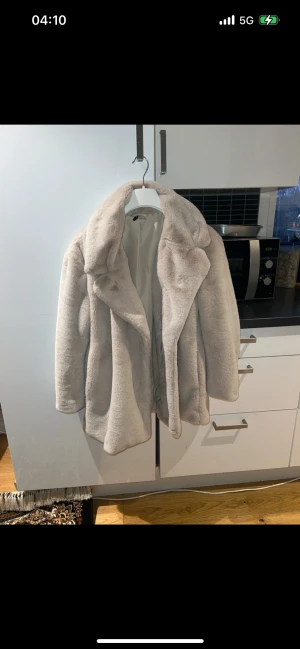 Beige pälsjacka från Divided L - Säljer en fluffig och stilren beige pälsjacka från Divided i storlek L. Jackan har bred krage, mjukt foder och en oversized look som ger en cool vibe. Perfekt för kalla dagar när du vill vara både varm och snygg.