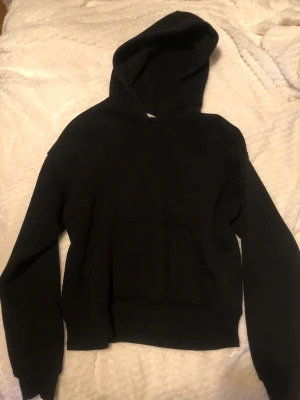 Svart hoodie från Gina Tricot XXS - Svart hoodie från Gina Tricot, basically basics-kollektionen. Klassisk modell med huva och stor magficka framtill. Har andvänds få gånger. 🖤