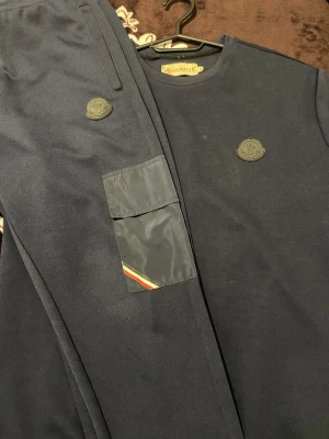 Mörkblå mjukisbyxor från Moncler - Snygga mörkblå mjukisbyxor från Moncler med en cool patchficka med diskret röd och vit detalj. Byxorna har Moncler-logga på benet och är gjorda i mjukt bomullsmaterial. Perfekt för chill eller streetwear.