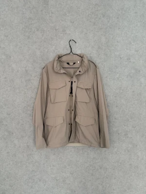 Aspesi Jacka - Snygg beige jacka från Aspesi med fyra stora fickor framtill och dragkedja med svart band. Jackan har klassisk krage, knappar och är tillverkad i lätt polyester. Skriv för fler frågor eller bilder 🤝🏼