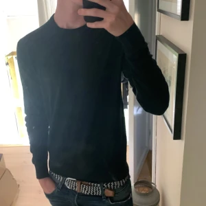 Grön stickad tröja från Uniqlo - En stilren svart stickad tröja från Uniqlo i storlek S. Tröjan har rund halsringning och långa ärmar, perfekt för lager-på-lager eller som den är. Enkel och clean look som funkar till jeans eller chinos.