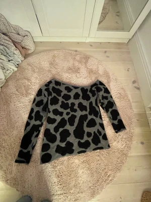 Grå offshoulder stickad tröja med leopardmönster - Säljer en super söt stickad offshoulder tröja i grått med svart leopardmönster. Storlek står inte men jag skulle gissa på M