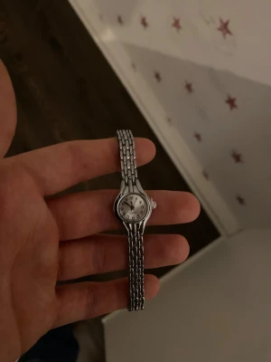 Rostfri Silverklocka  - Klockan är i ett fint skick utan repor eller andra defekter. Sen snurrar på fint med ett helt nytt batteri installerat.  Klockans längd/storlek går att justera hemma från 8 cm längd till 19 cm längd med hjälp av en nål 📌