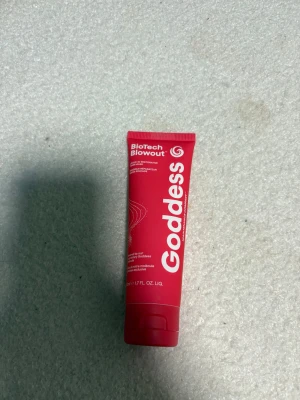 Goddess BioTech Blowout röd tub - En snygg röd tub från Goddess med texten BioTech Blowout. Tuben är i plast och har en modern design med vita detaljer. Perfekt att ha i sminkväskan för en fräsch look.använd en gång . Köpt på Lyko