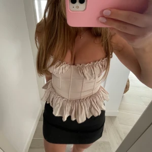  korsettopp med volangdetaljer - Beige/ljusrosa korsett topp från h&m. Storlek 36/s skulle kunna passa 34/xs också.  (Lånade bilder)