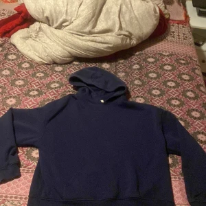 Mörkblå hoodie med huva - En stilren mörkblå hoodie med huva och långa ärmar. Tröjan har en klassisk passform och är tillverkad i mjukt material som känns skönt mot huden. Perfekt för dig som gillar en enkel och clean look.