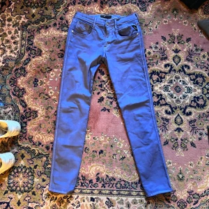 Blå Replay Anbass jeans 29/32 - Säljer ett par blå Replay Anbass jeans i midwaist-modell. Byxorna har klassisk femficksdesign, smal passform och är tillverkade i mjukt bomullsmaterial med lite stretch. Perfekta för dig som gillar stilrena och bekväma jeans. Midja 38cm längd 102cm (31)