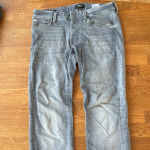 Slim Glenn ljusblå jeans Jack & Jones - Ljusblå jeans från Jack & Jones, modell Slim Glenn. Klassisk femficksdesign med smal passform och raka ben. Jeansen har bälteshällor, dragkedjegylf och subtila sömdetaljer på bakfickorna. Perfekta för en avslappnad och stilren look. Defekter bild 3