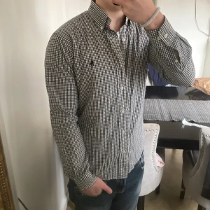 Rutig ralph lauren skjorta - Otroligt fin och stilig rutig Ralph lauren skjorta i riktigt fint skick.  14 1/2, 32/33. Sitter som S. Modellen är 180cm och 72kg. Svart, vit och mörkgråa rutor.