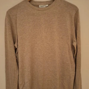 Beige långärmad tröja från Kappahl - En stilren beige långärmad tröja från Kappahl i storlek S. Tröjan har rund halsringning och är tillverkad i mjuk bomullsmix, perfekt för lager-på-lager. Enkel och clean look som funkar till allt.