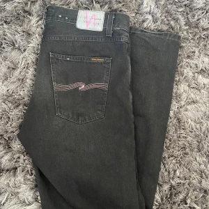 Nudie Jeans W34 L34 Limited Edition Nudie x Jeff Olsson - Limited Edition Nudie Jeans x Jeff Olsson                W34 L34 Straight passform i svart färg med lila detaljer. Nypris 2200kr