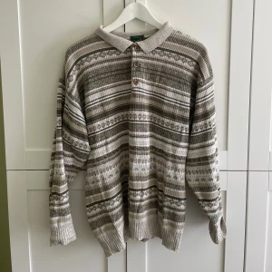 Stickad vintage tröja  - Stickad vintage tröja i beige och grå toner. Tröjan har krage, tre knappar framtill. Använt men bra skick - inga defekter. 