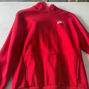 Röd Nike hoodie med logga XL - Riktigt snygg röd hoodie från Nike i storlek XL. Klassisk design med vit Nike-logga på bröstet, huva och känguruficka framtill. Mjuk och skön, perfekt för chill eller träning. Passar dig som gillar sportig och enkel stil.