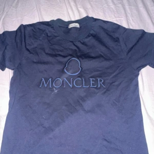 Blå t-shirt från Moncler - Snygg blå t-shirt från Moncler med det ikoniska logotyptrycket på framsidan. Perfekt för en avslappnad stil. Tillverkad i mjukt material för extra komfort.