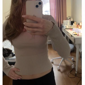 Beige ribbad långärmad topp - Snygg beige långärmad topp med ribbade detaljer och tight passform. Toppen har en enkel och stilren design med fyrkantig halsringning och är tillverkad i ett stretchigt material.