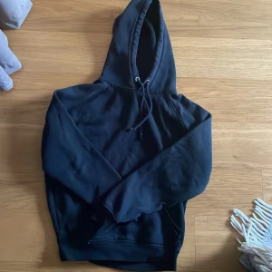 Svart hoodie från BikBok XS - En svart hoodie från BikBok i storlek XS. Tröjan har huva med snörning och en klassisk känguruficka framtill. Mjuk insida och långärmad modell, perfekt för chill dagar eller när du vill ha en enkel och stilren look.