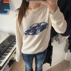 Vit stickad tröja med blå bilmotiv - Vit stickad tröja med ett stort blått bilmotiv på framsidan. Tröjan har rund hals och är super skön. Ifårn subdued och köpt för runt 600kr. Jätte bra skick och super cool. Storlek XS men passar även om man brukar ha S/M i tröjor jag är 164