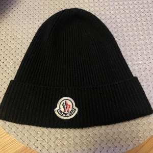 Svart ribbstickad mössa från Moncler - Mössa från moncler. Typ helt ny använd ett fåtals gånger och är självklart äkta och köpt från NK för 2300kr